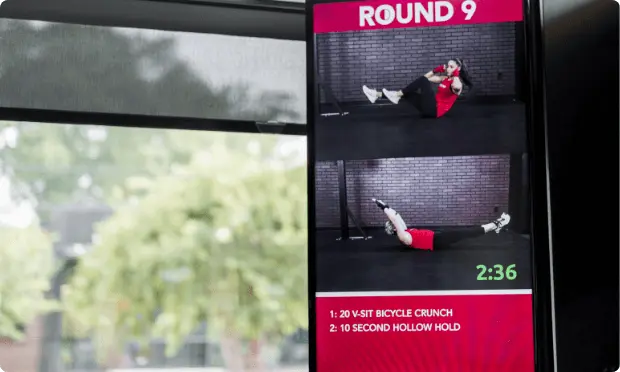 Photo of a screen showcasing an innovative fitness technology for Round 9, featuring a finess screen demonstrating exercises, with the timer set at 2:36.